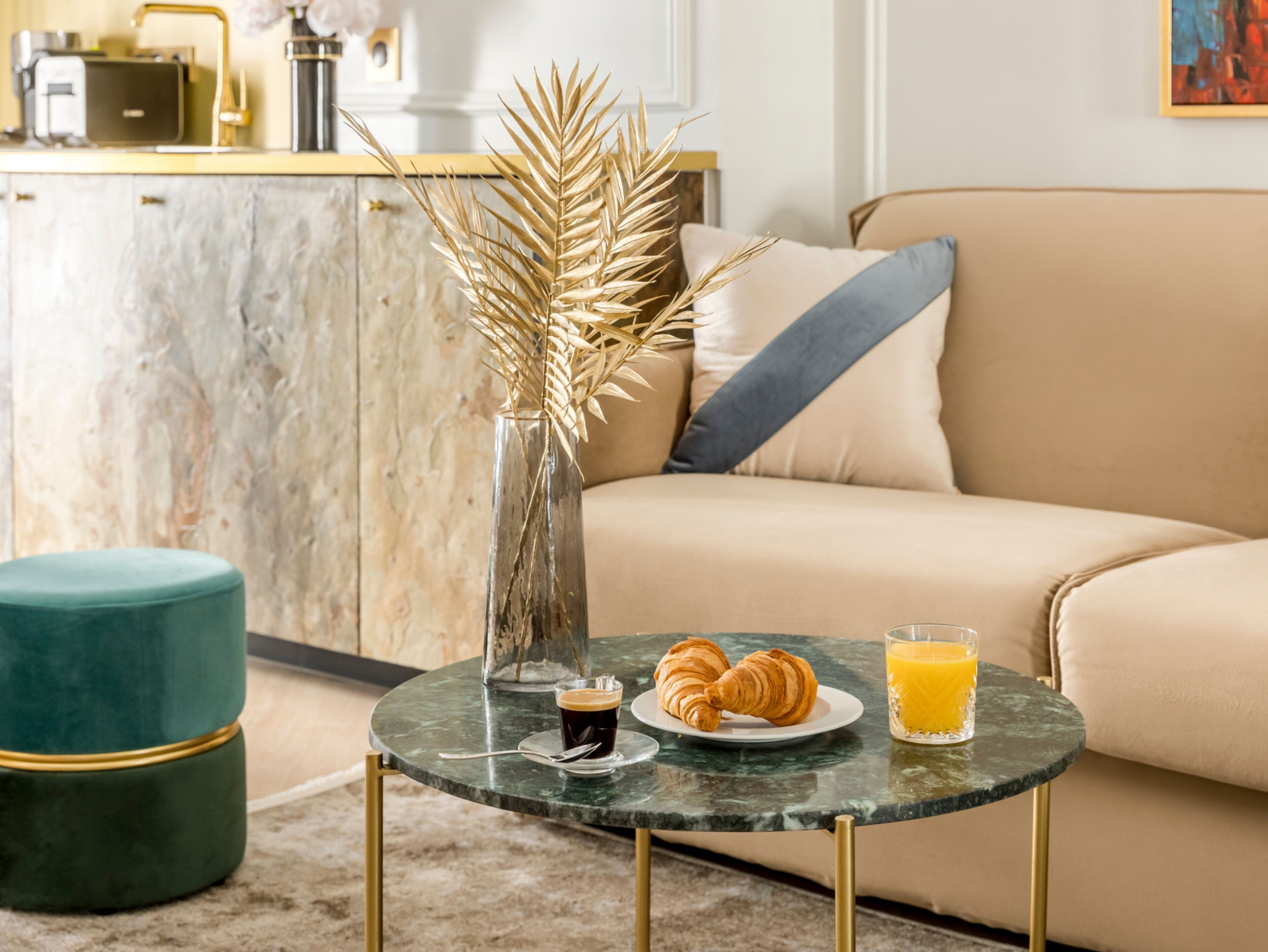 Een moderne woonkamer met een marmeren salontafel, een bank en een decoratieve vaas met gedroogde planten.