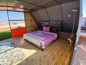 Habitación tipo tienda con cama, una mesita y vistas al exterior.