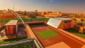 A rooftop terrace with a green lawn, a small seating area, and a water feature. - Chateau Nougat Marrakech (Tameslouht)