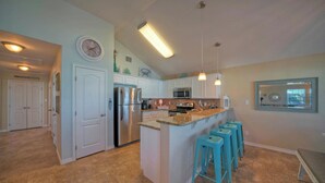 A modern kitchen with white cabinets, stainless steel appliances, and a central island with bar stools.