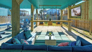 A covered outdoor seating area with a sofa, chairs, and a small table.