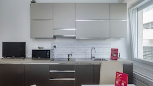 Una cocina moderna con electrodomésticos de acero inoxidable, un salpicadero de ladrillo blanco y un ventanal que proporciona luz natural.