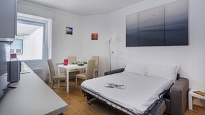 Una habitación de hotel moderna con cama, escritorio, silla, mesa y un ventanal grande.