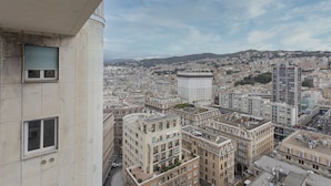 Un edificio de gran altura con varios pisos, amplias ventanas y vistas a un paisaje urbano con diversos edificios y una colina distante.