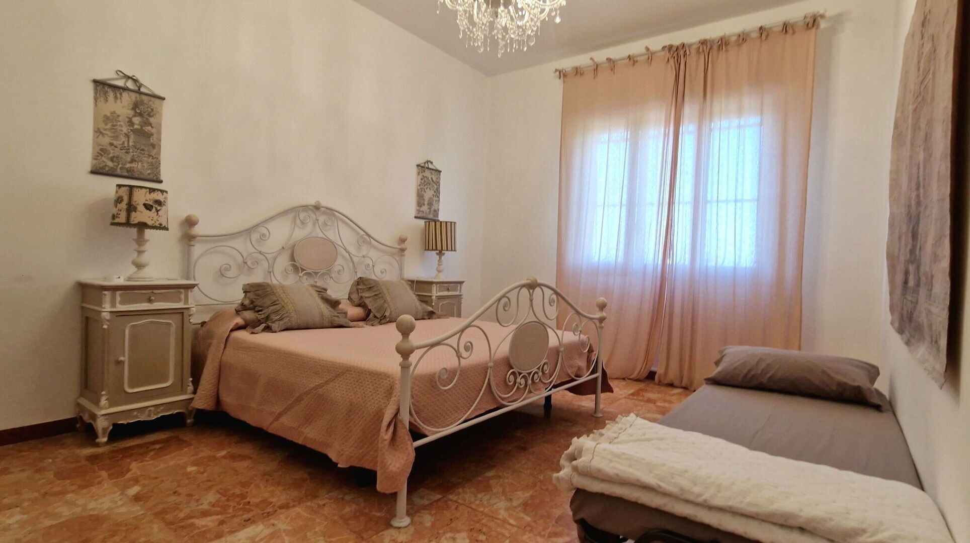 A bedroom with a bed, bedside tables, a lamp, a nightstand, a dresser, and a window with curtains.