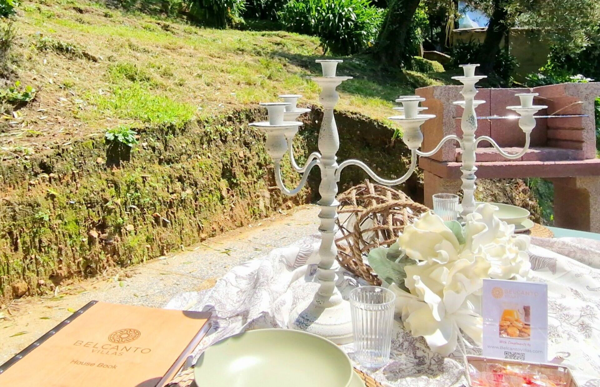 A table set with white tableware and a house book titled 'BELCANTO VILLAS'.