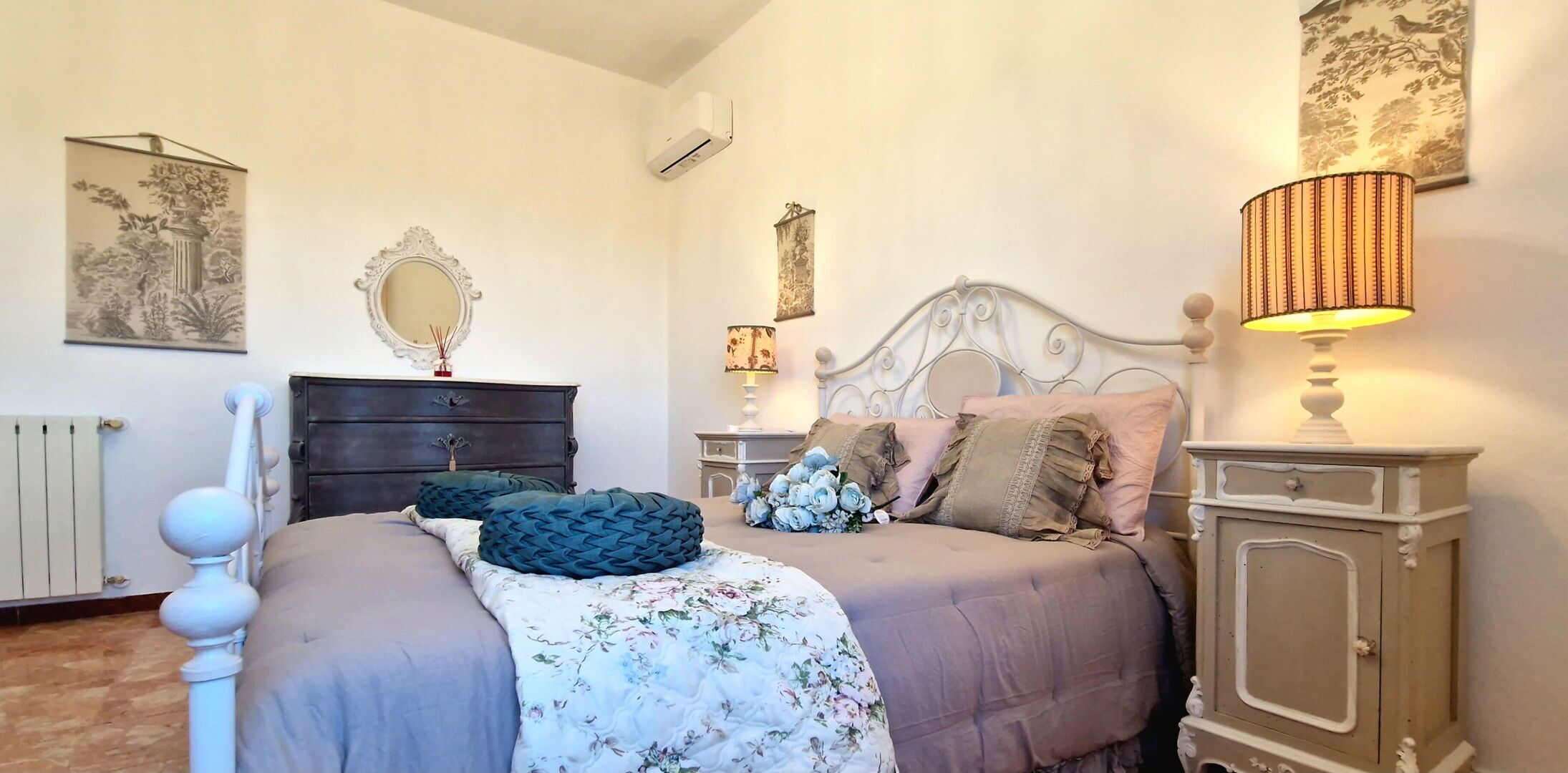 A bedroom with a bed, dresser, mirror, and wall art.