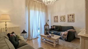 A cozy living room with a sofa, a coffee table, a lamp, and a window with curtains.
