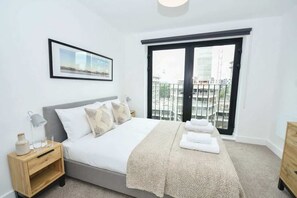 Une chambre à coucher avec un lit, une table de chevet, une fenêtre donnant sur un beau paysage et un tableau encadré au mur.