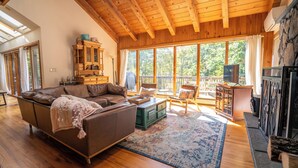 A spacious living room with a wooden ceiling, a large sofa, a coffee table, and a television.