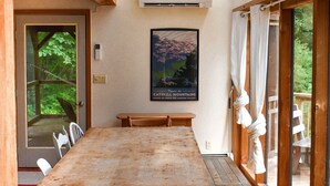 A dining area with a wooden table and chairs, a bench, and a large window with a view of greenery.