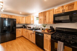 Una cocina moderna con armarios de madera, un refrigerador negro, una estufa y un lavavajillas.