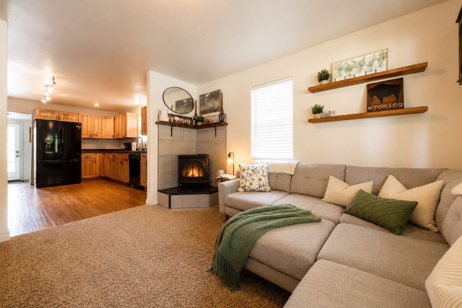 Una sala de estar con sofá, chimenea y cocina al fondo.