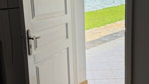Une porte ouverte donnant sur un patio avec vue sur l’océan.