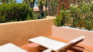 A terrace with two lounge chairs and a small table, surrounded by a low wall and various plants. - Sunset Suite Sardinia 0.4 (Porto Rotondo)