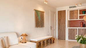 A modern living room with a sofa, a bench, a lamp, and a bookshelf. - Sunset Suite Sardinia 0.4 (Porto Rotondo)