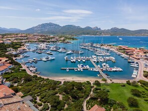 Vista aérea de uma marina com inúmeros barcos atracados, rodeada por edifícios residenciais e vegetação exuberante.