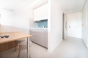 A modern kitchen with white cabinets, a patterned backsplash, and a wooden dining table with chairs.