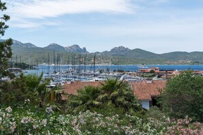 A marina with boats, a coastal town, and mountainous background. - Sunset Suite Sardinia 0.9 (Porto Rotondo)
