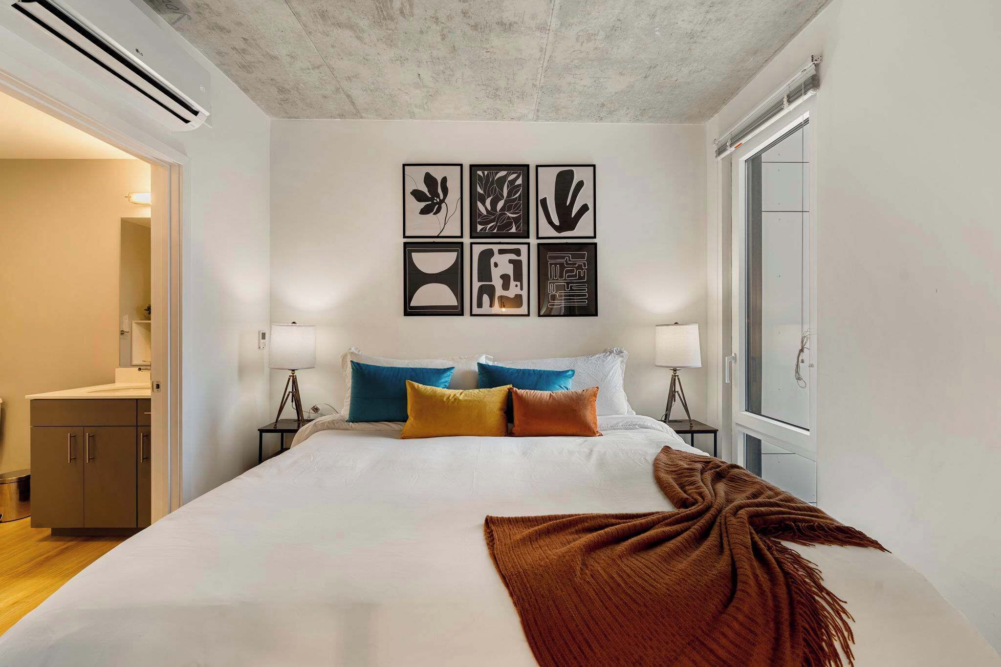 Una camera d'albergo con un letto grande, un condizionatore d'aria a parete e una finestra vista.