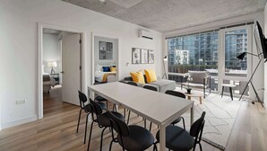 Ein modernes Wohnzimmer mit Essbereich, großen Fenstern und Blick auf die Stadt.