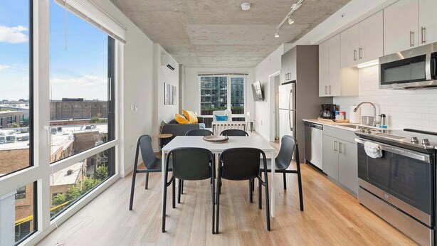 A modern kitchen with a dining area, large windows, and a city view. - Modern 2BR Retreat Near Old Town & Lincoln Park (Chicago)