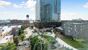 A modern high-rise building with a glass facade, surrounded by smaller buildings and a parking area. - Modern 2BR Retreat Near Old Town & Lincoln Park (Chicago)