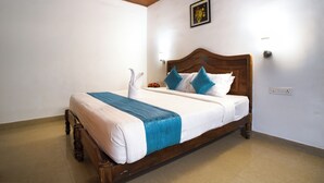 Una cama individual con cabecera de madera, ropa de cama blanca y detalles en azul.