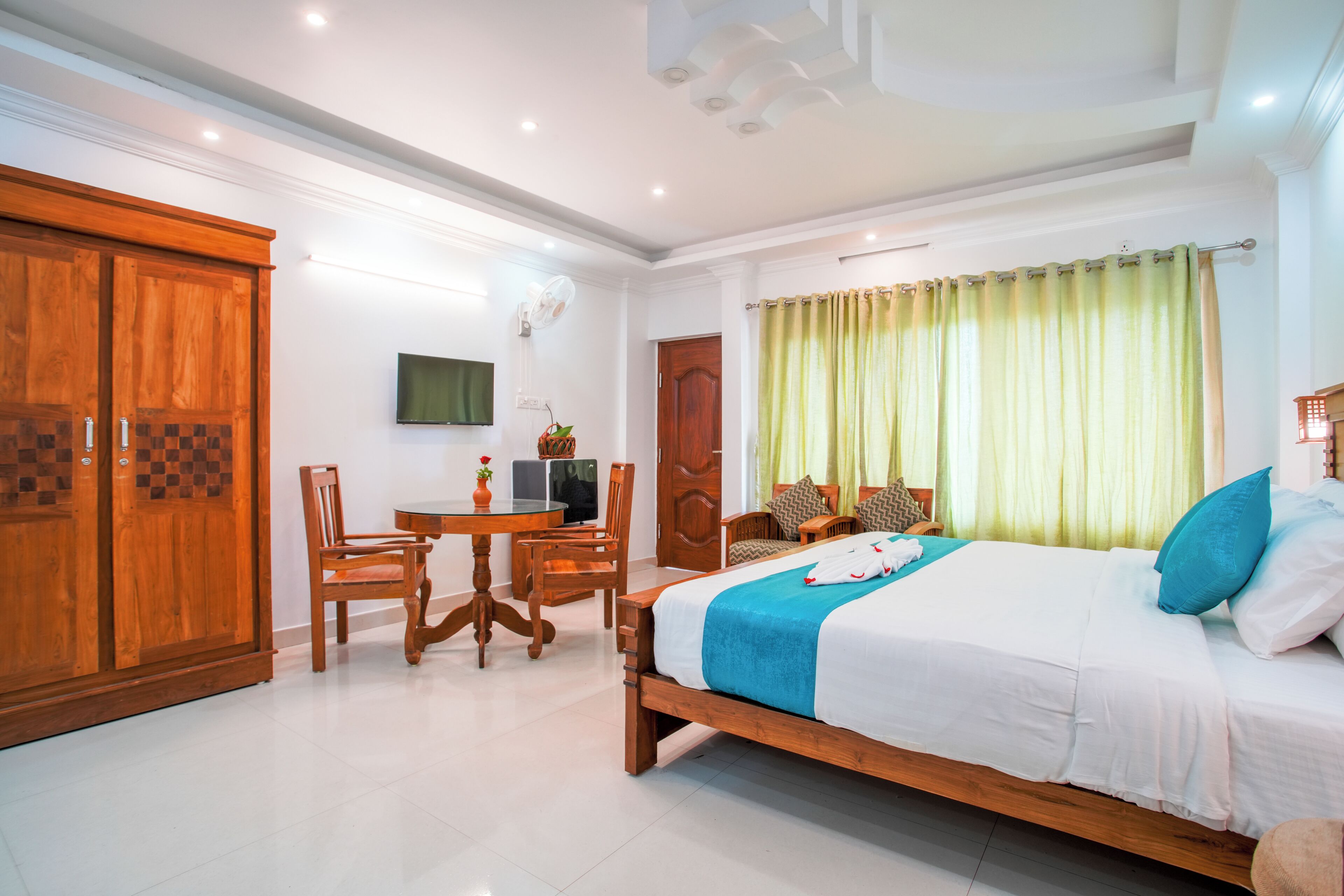 A hotel room with a bed, a desk with a chair, a television, and a wardrobe.