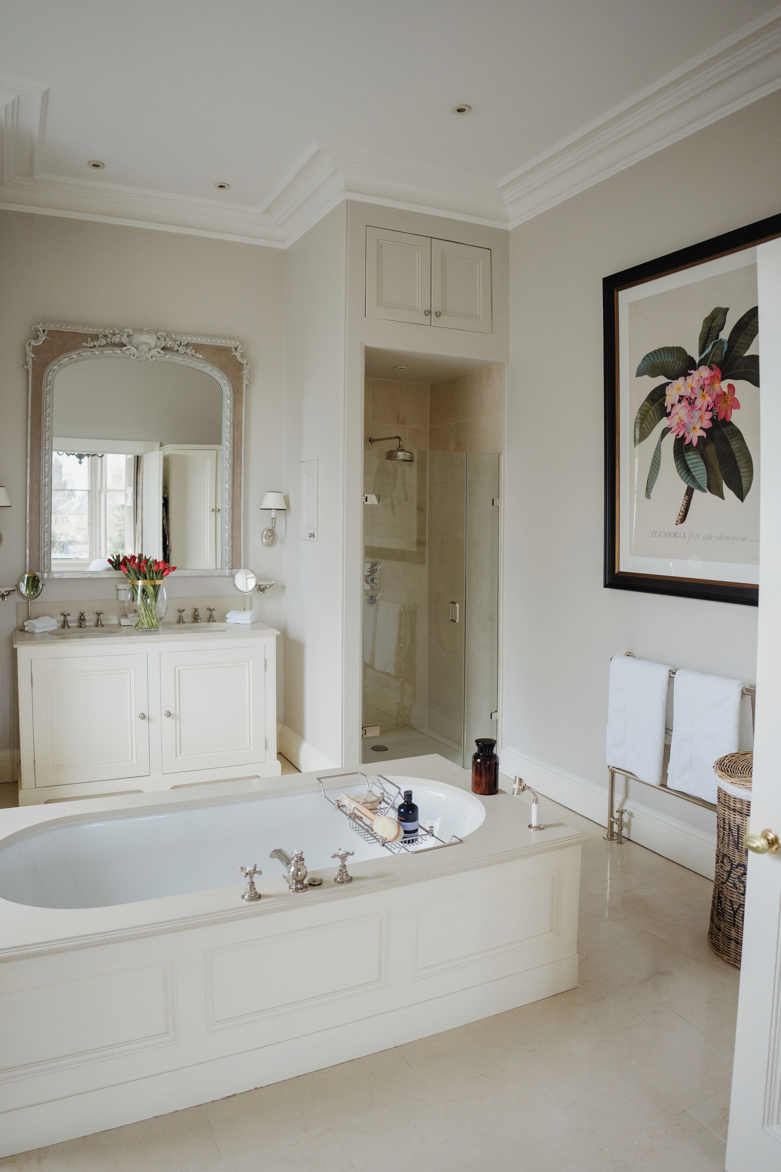 A spacious bathroom with a large bathtub, a vanity with a mirror, and a framed botanical print on the wall.