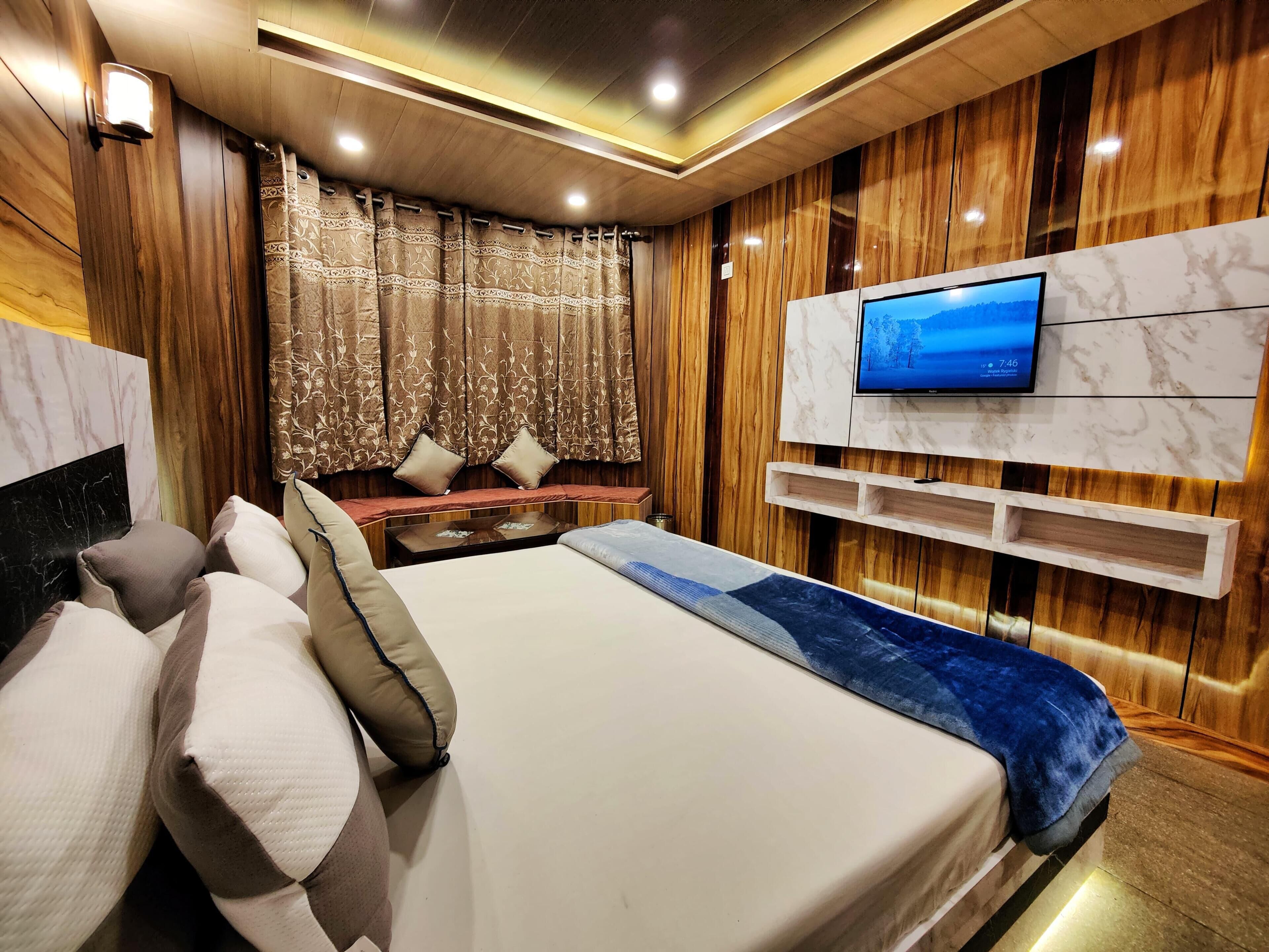 A modern hotel room with a large bed, a TV mounted on the wall, and a wooden accent wall.