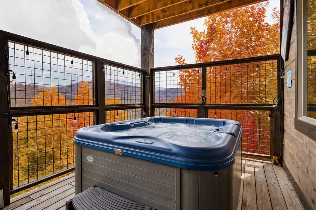 Un jacuzzi en una terraza de madera con vistas a follaje otoñal y montañas.