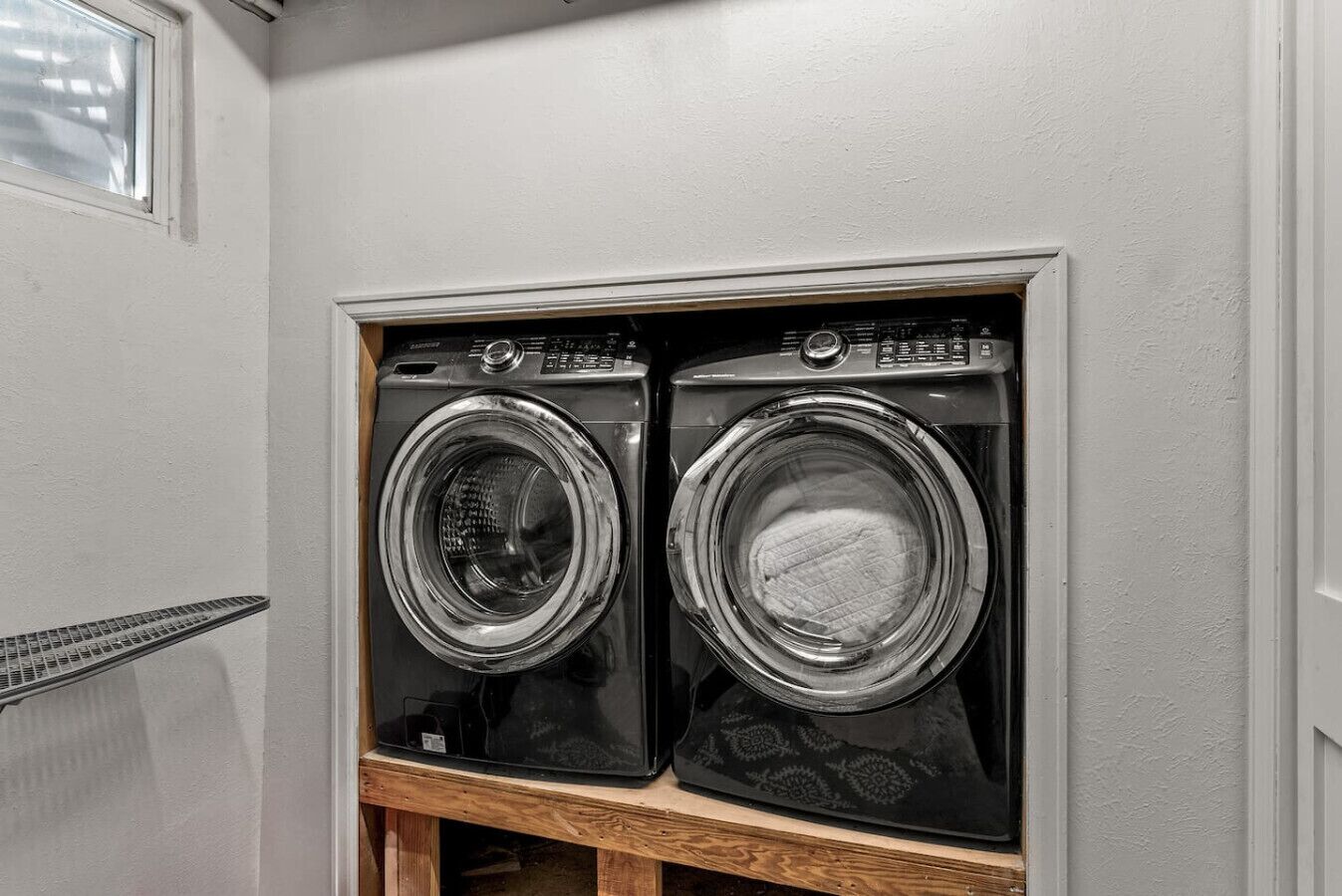 A laundry room with two front-loading washing machines in a wooden cabinet.