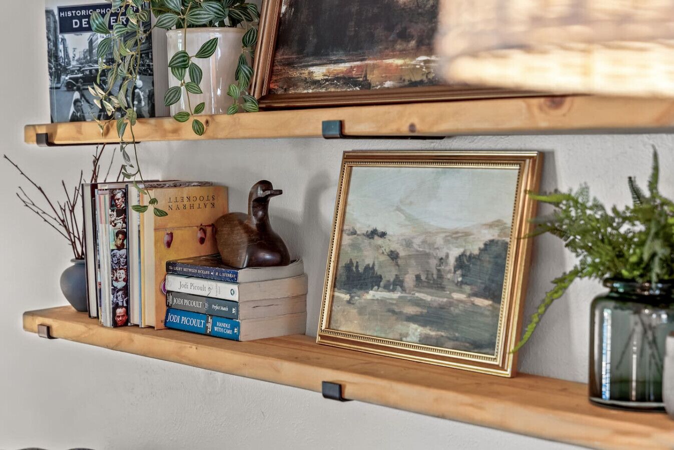 Deux étagères en bois, ornées de livres, d’objets décoratifs et d’œuvres d’art encadrées.