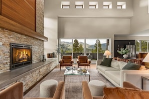 A modern living room with a stone fireplace, leather chairs, a glass coffee table, and a sofa. - Summit Solace | LUXE 360° Views • Hot Tub • Games (Bailey)