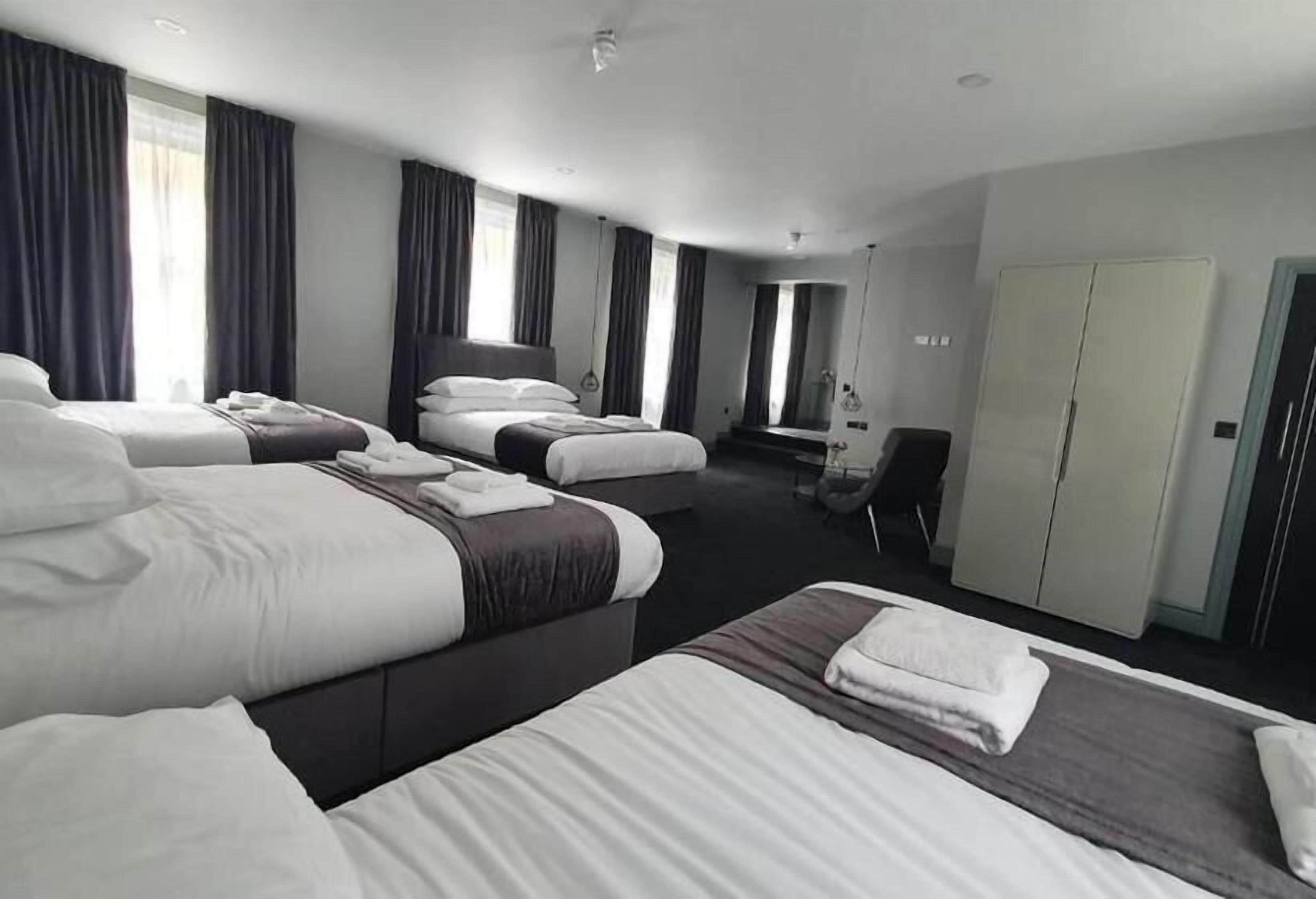 A hotel room with three beds, a desk, and a wardrobe.