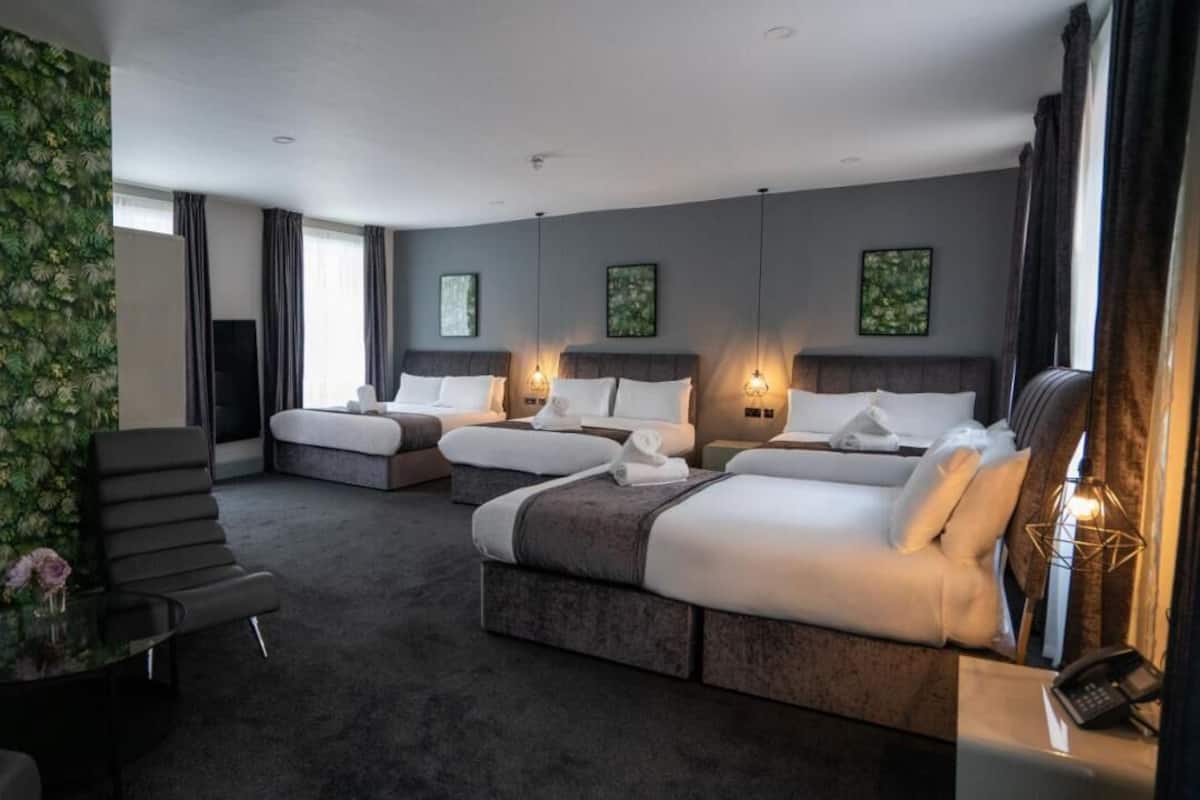 Une chambre d’hôtel avec deux lits, un canapé, une petite table et un mur décoratif.