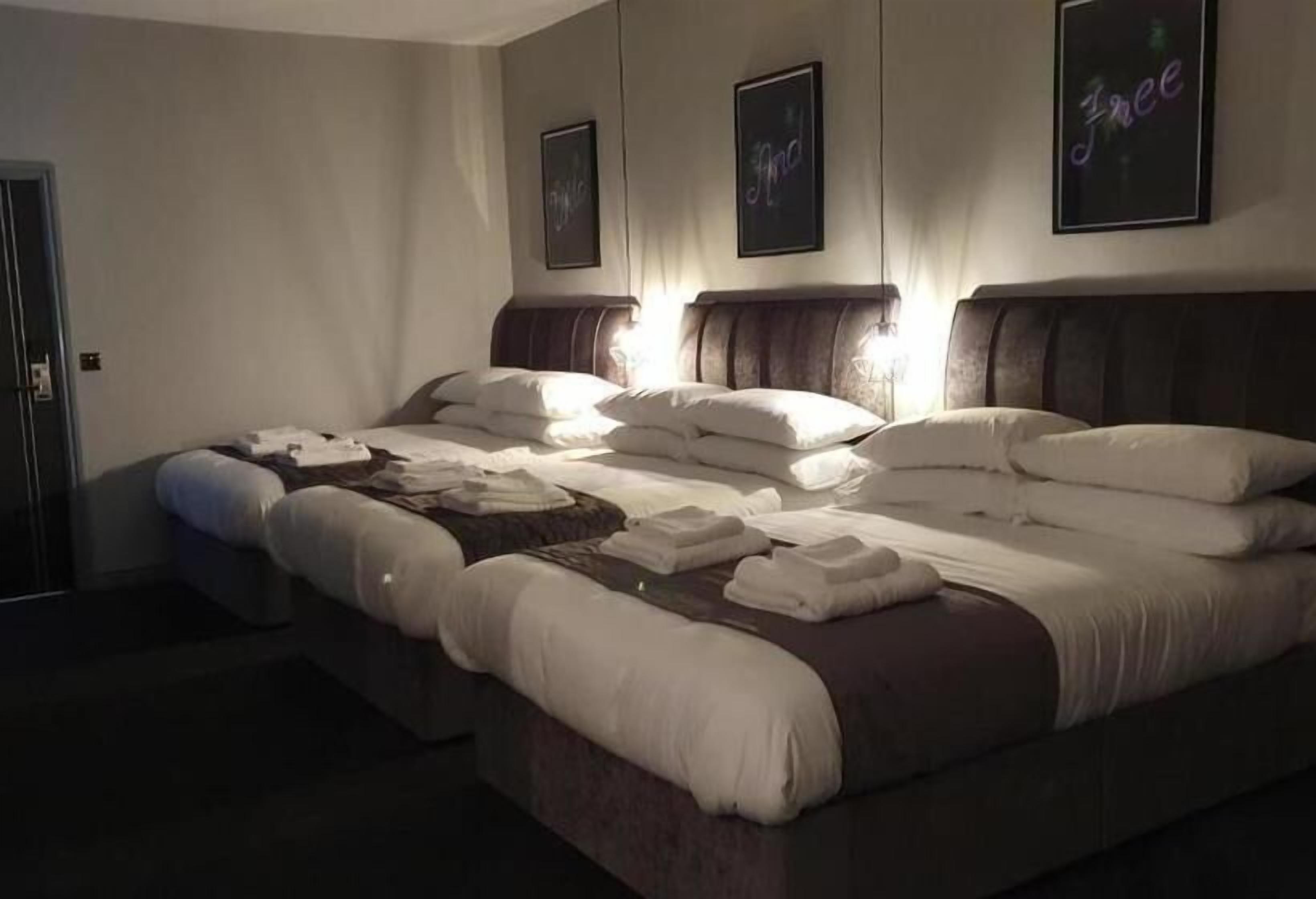A large bed with multiple pillows and blankets, a headboard, and framed pictures on the wall.