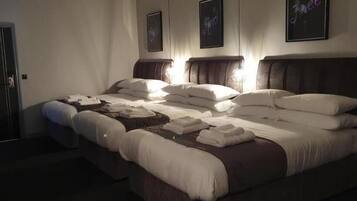 A large bed with multiple pillows and blankets, a headboard, and framed pictures on the wall.