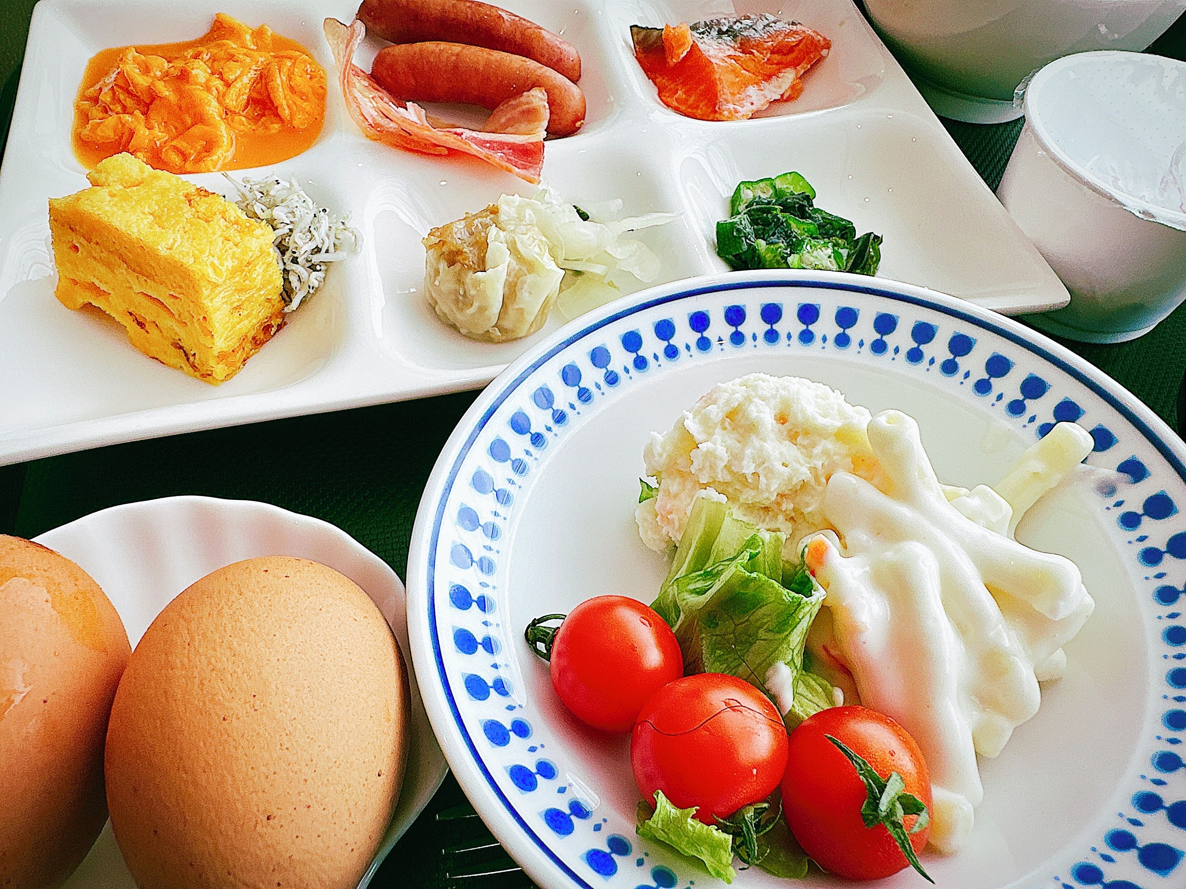 A table with various dishes including eggs, tomatoes, and a plate with a blue pattern.