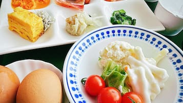 A table with various dishes including eggs, tomatoes, and a plate with a blue pattern.