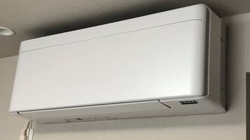 A white air conditioning unit mounted on a wall with a power outlet below it.