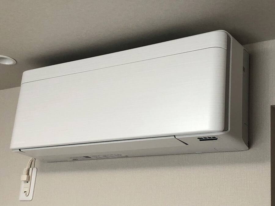 A white air conditioning unit mounted on a wall with a power outlet below it.