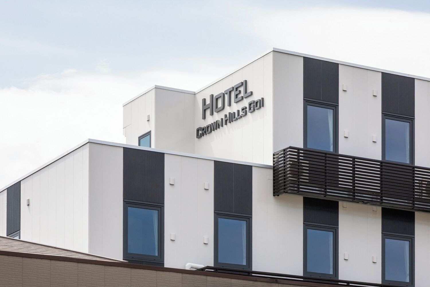 A modern hotel building with a flat roof, large windows, and a prominent sign reading "HOTEL CROWNHILL".
