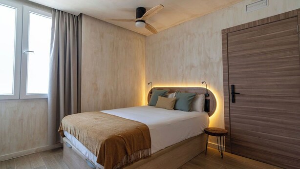 Une chambre à coucher comprenant un lit, un ventilateur de plafond, une table de chevet et une armoire.