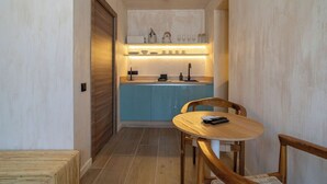 Une cuisine de taille réduite avec un plan de travail bleu, des placards en bois et une table ronde en bois, accompagnée de chaises.