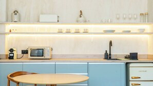 Une cuisine équipée d’un four à micro-ondes, d’un grille-pain et d’une machine à café sur le plan de travail, d’un évier et d’une table avec des chaises.