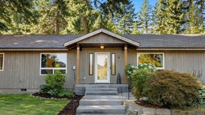 A two-story house with a front porch, a garage, and a well-maintained lawn. - 6.5 acres all to yourself! Dog-Friendly Creekside Home w/ Hot Tub, Game Room. 15 minutes to town (White Salmon)