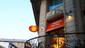 Un hotel con un letrero que dice "AMBER HOTEL" y un balcón con barandas de hierro decorativas.