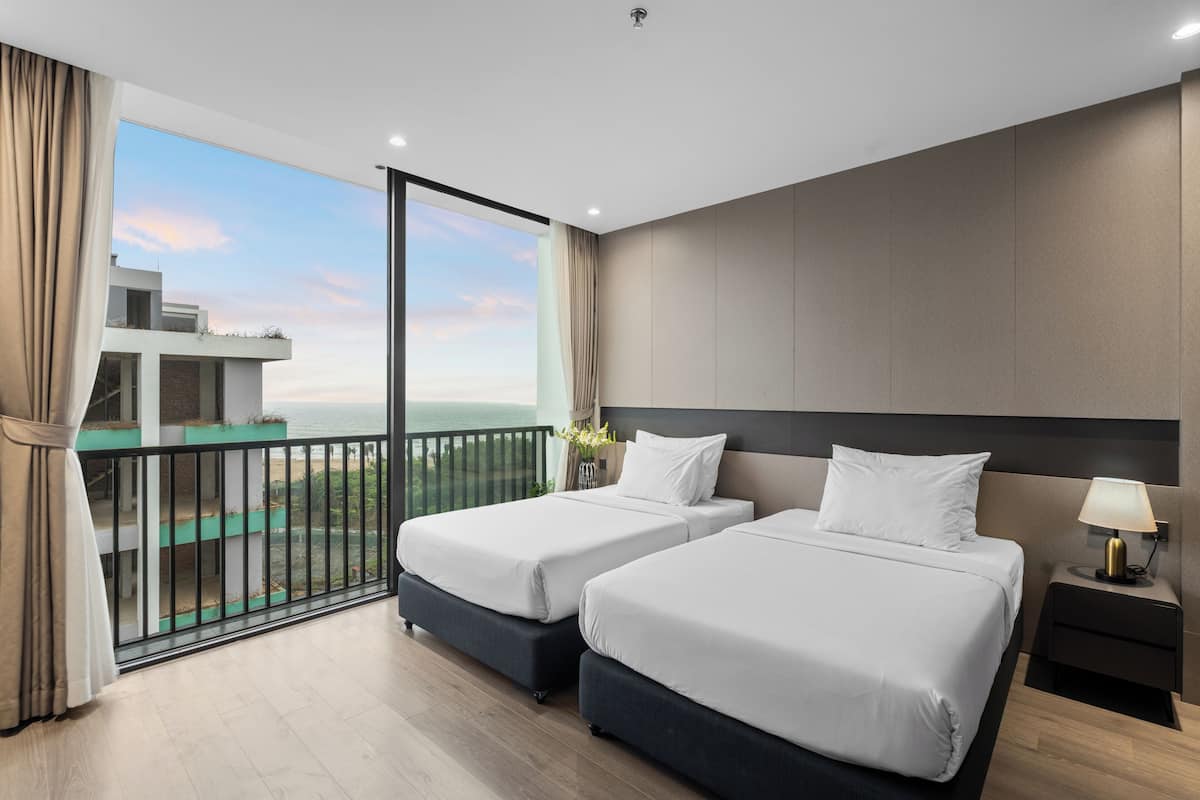 A hotel room with two beds, a balcony with a view of the sea, and a modern design.
